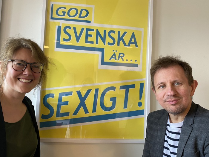 Foto på Maria Bylin och Anders Svensson som ser in i kameran och ler. Bakom dem syns en poster med texten "God svenska är... sexigt!"
