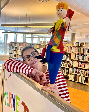 En kvinna i ett bibliotek, håller upp en docka.